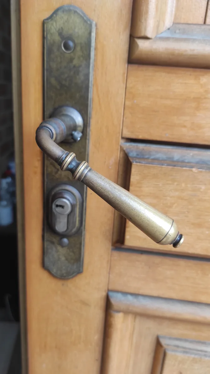 Poignée laiton ancienne et cylindre sur porte en bois par AMG Serrurerie