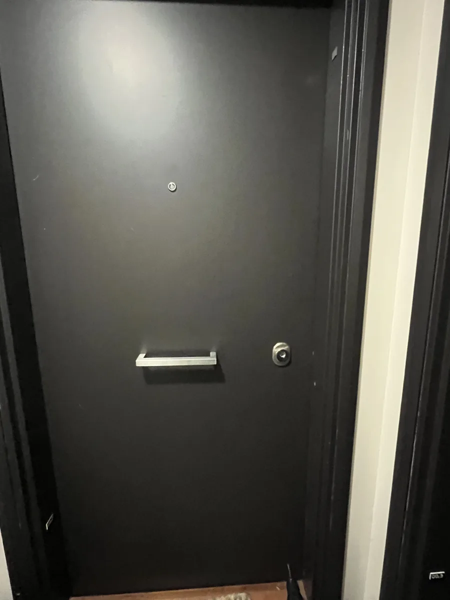 Porte blindée noire avec barre de tirage inox par AMG Serrurerie